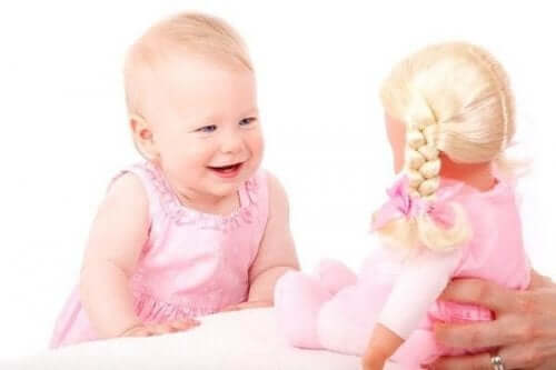 Bambina che ride guardando una bambola