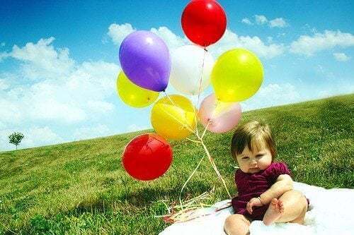 Bambino con palloncini colorati su un prato