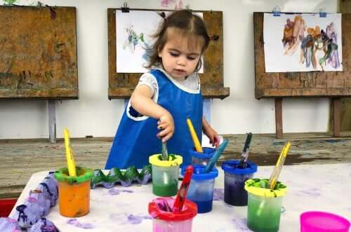 bambina che gioca con i colori e dipinge dei quadri
