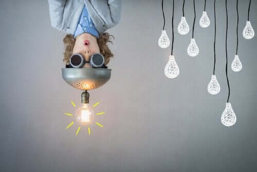 Il metodo Design Thinking è una metodologia che consente di trovare soluzioni nuove. Bambino a testa in giù con lampadina in testa.