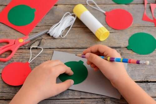 bambino che disegna e ritaglia palle di natale colorate
