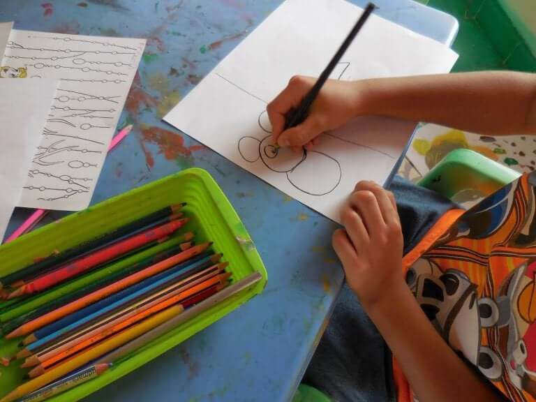 Bambino che disegna e matite colorate