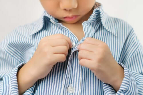 bambino che si abbottona la camicia da solo