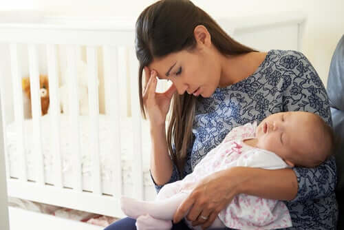 Mamma depressa con figlio neonato in braccio.