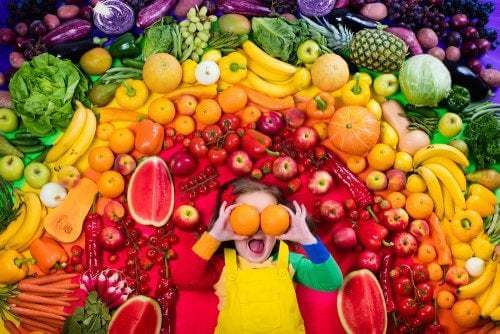 Bambina circondata da frutta e verdura