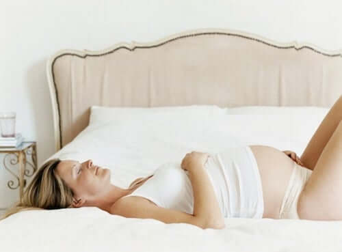 donna incinta che riposa sdraiata sul letto