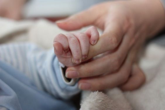 Mano di neonato stringe il dito della madre