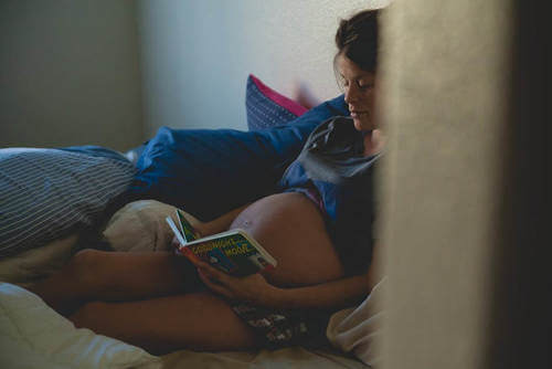 Donna incinta legge. Bebè dentro l'utero.