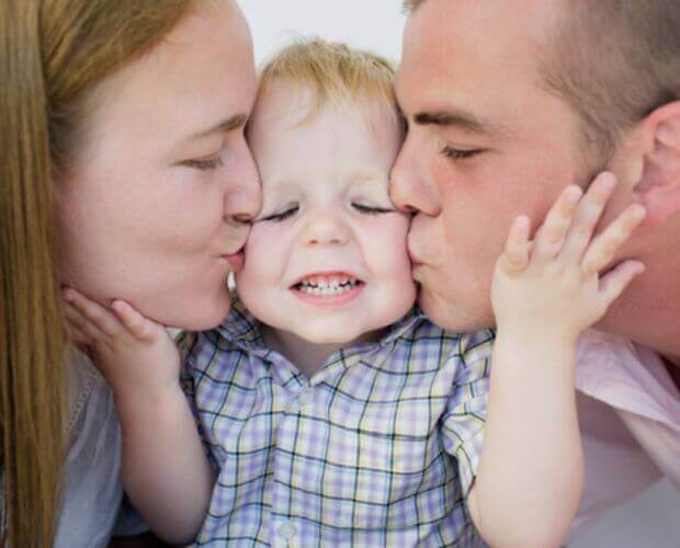 Papà e mamma baciano il bambino