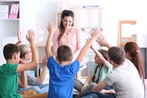 Bambini con mano alzata per rispondere alle domande della maestra.