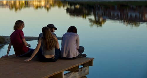 ragazzi seduti sulla banchina di un lago