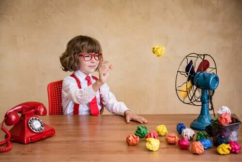 Bambino che gioca con delle palle di carta e un ventilatore.