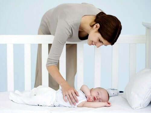 Mamma che accarezza neonato che dorme.