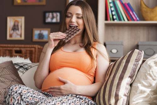 Donna incinta che mangia cioccolato.