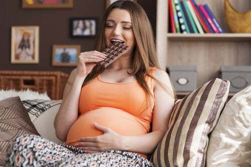 Donna incinta che mangia cioccolato.