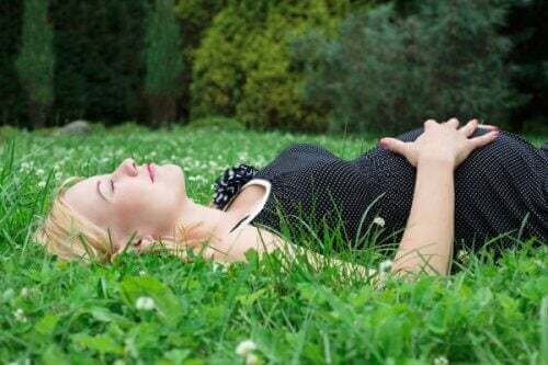 Donna sta sdraiata incinta su un prato.