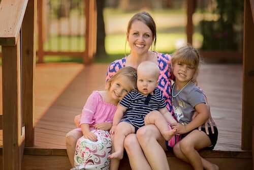 Mamma seduta che abbraccia i figli.