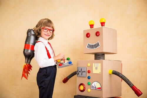 Bambino che gioca con un robot di cartone.