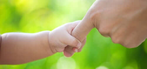 Neonato che tiene la mano del padre.