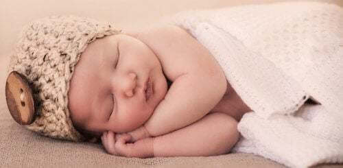 Bambino che dorme con un cappello in testa.