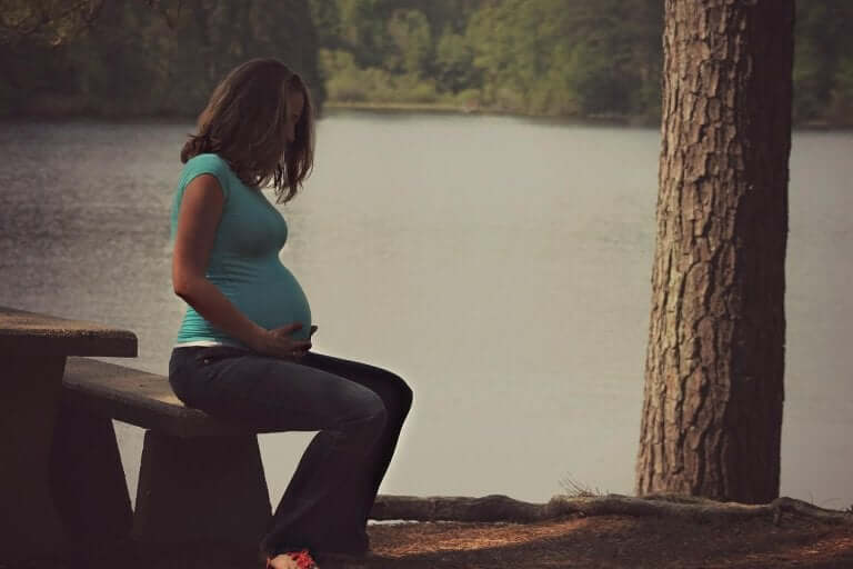 Donna incinta seduta al parco.