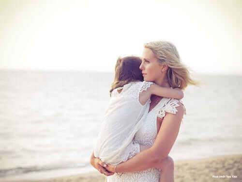 madre che tiene in braccio la figlia sulla spiaggia
