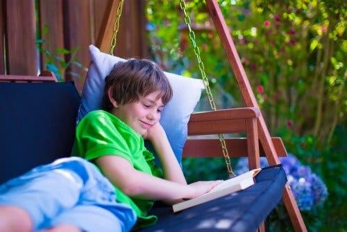 Ragazzo che legge un libro sul divano a dondolo