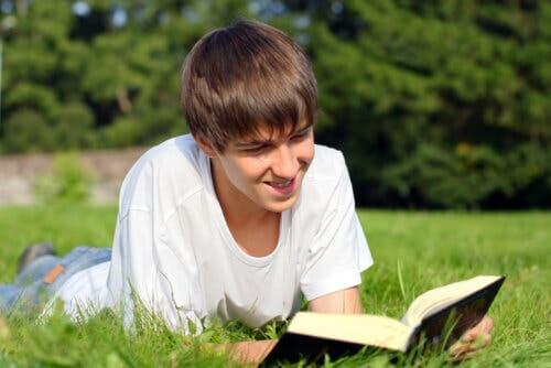 Ragazzo che legge un libro sdraiato sul prato