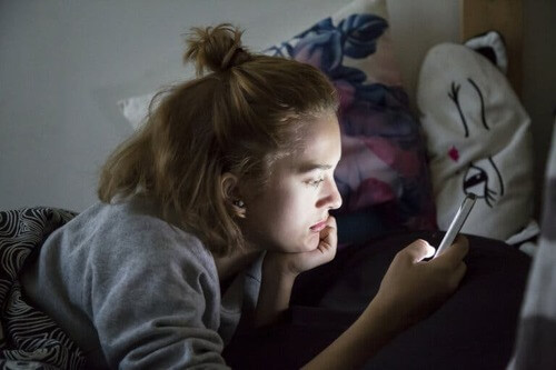 Tendenze pericolose sui social: ragazza usa un cellulare.