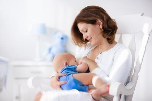 donna allatta un bambino su una sedia a dondolo