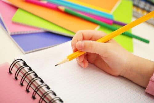 Bambino che scrive con la matita su un foglio di carta
