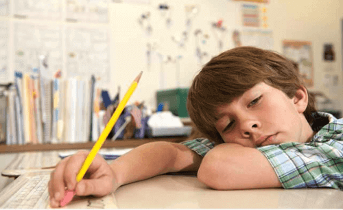 Bambino pigro che dorme sul banco.
