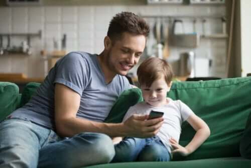 Padre e figlio seduti sul divano che utilizzano un'app sul telefono.
