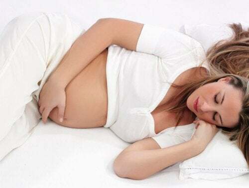 Riposare correttamente durante la gravidanza. Donna incinta sdraiata a letto.