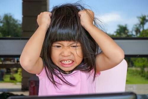 Bambina arrabbiata con le mani in testa che si tira i capelli.