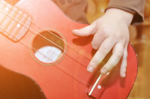 Bambino che suona una chitarra rossa.