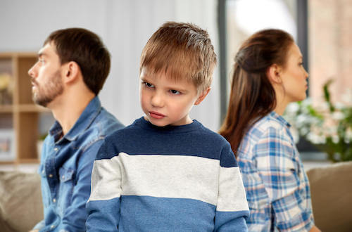 Bambino arrabbiato che volta le spalle ai genitori.