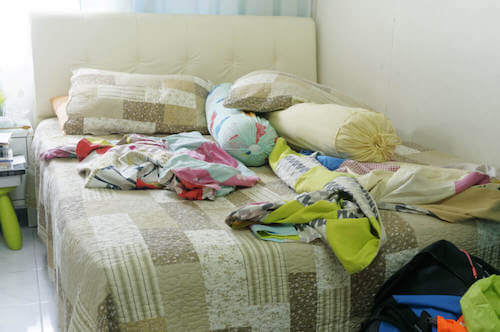 Letto pieno di vestiti e cuscini.