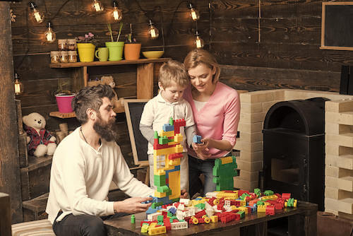 Padre e madre che giocano col figlio facendo le costruzioni.