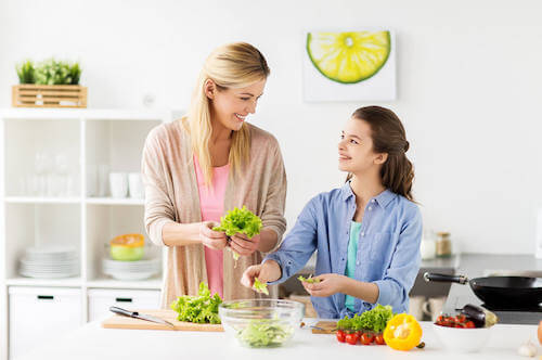 Madre e figlia vegana che preparano un'insalata.