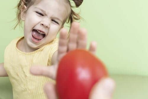 Bambina che si rifiuta di mangiare una mela.