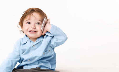 Bambino piccolo che sorride e che parla al telefono.