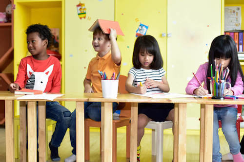Bambini in età prescolare che giocano e disegnano in classe.