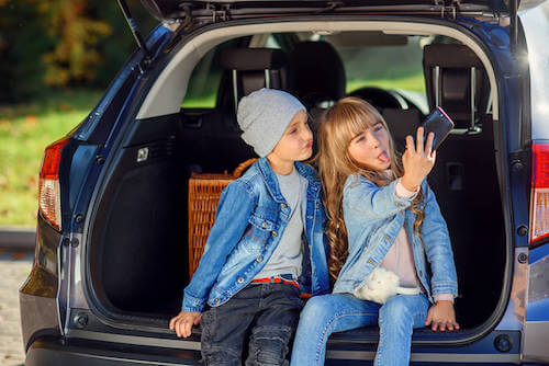 Bambini seduti nel bagagliaio della macchina che si fanno un selfie.