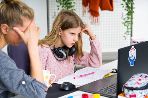 Madre che aiuta la figlia adolescente a studiare perché la ragazza ha delle difficoltà di apprendimento.