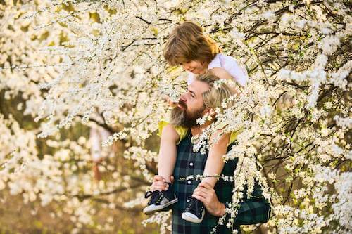 Padre e figlio che passeggiano tra gli alberi fioriti.