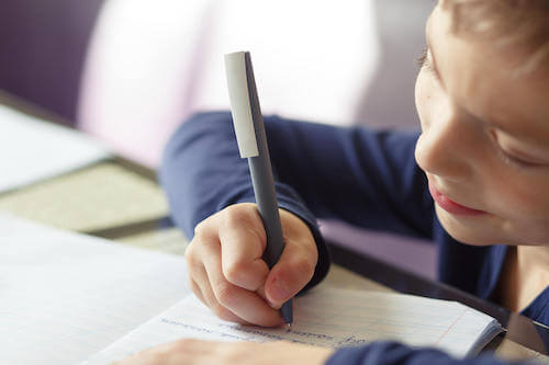 Bambino che scrive delle frasi su un quaderno per migliorare l'ortografia.
