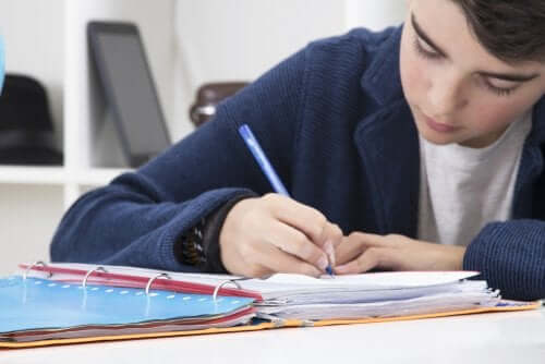 Imparare a scrivere un riassunto. Bambino che scrive su un quadernone.