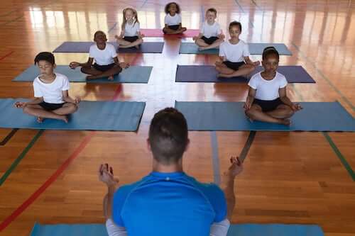 Bambini che praticano yoga con il loro insegnante.