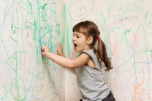 Bambina che scarabocchia sui muri.